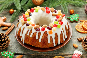 Bundt cake with fir-tree branches and gingerbread cookies on wooden table
