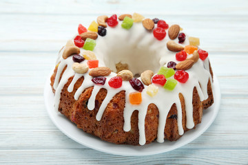 Bundt cake with candied fruit, almonds and cashew on wooden table