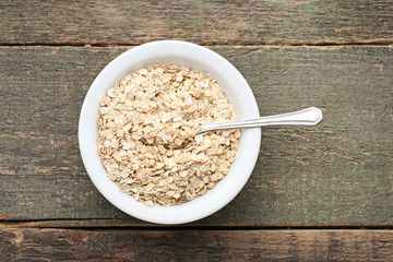 Oat flakes in plate with spoon on wooden table
