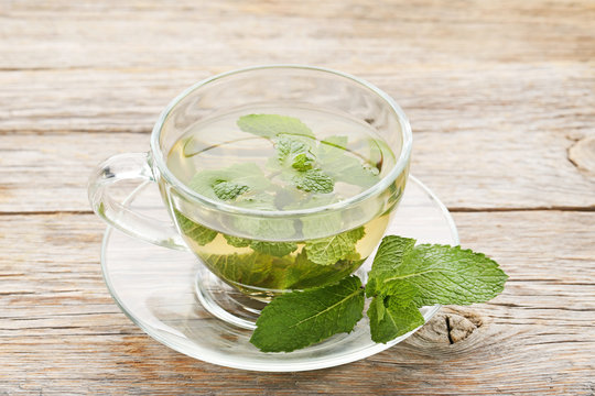 Cup of tea with mint leafs on wooden table