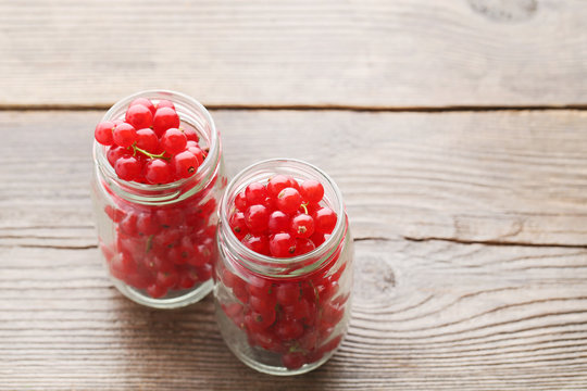 Red currants in bottles on grey wooden table