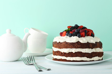 Delicious chocolate biscuit cake with teapot and cups on wooden table