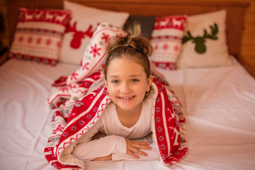 young girl underneath a blanket with christmas motive