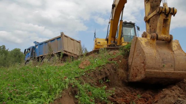 Construction Excavator Scooping and Dumping on Dirt Pile