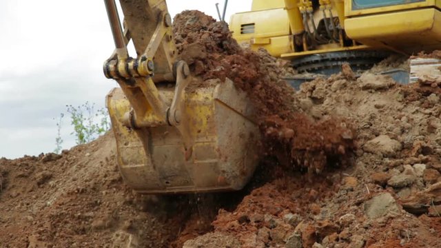 Construction Excavator Scooping and Dumping on Dirt Pile