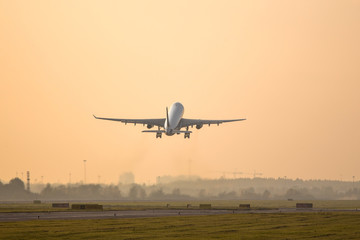 airplane taking off on sunset above the runway /plane fly up at sunset yellow sky background...