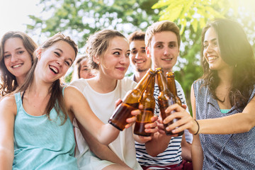 Group of students having fun, they clink with their beer
