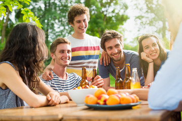 Group of young people gathered around a table outside to chat