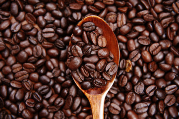 A wood spoon with roasted coffee. Coffee Beans Background. Close Up.
