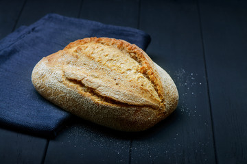 Photo of handmade white bread on black wooden background.