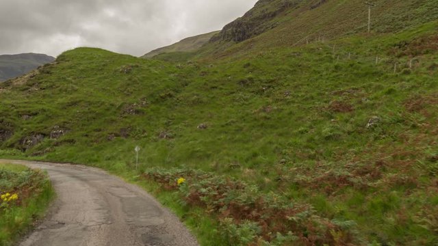 POV shot from a camera attached to the front of a vehicle driving through beautiful empty roads in the scottish highlands