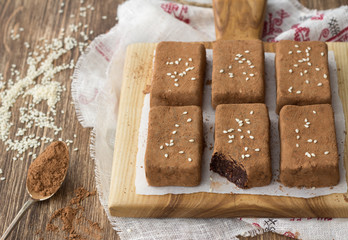 Chocolate sweets with dried fruits and sesame seeds on a wooden table, rustic style. Healthy homemade food