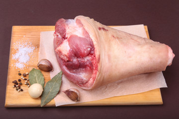Raw pork knuckle, Aromatic dried bay leaves, garlic, sea salt and spices on a cutting board. Selective focus. Ready for cooking.