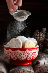 woman sprinkles homemade cookies with powdered sugar