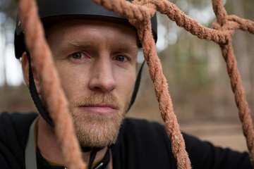 Portrait of man posing through a rope fence in the forest