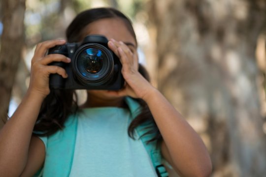 Little girl with backpack taking photos from dslr camera in the