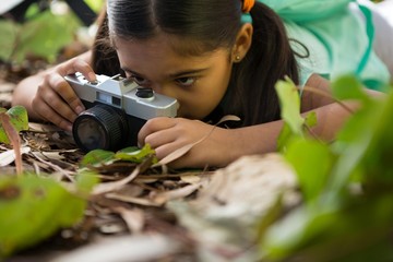 Little girl with backpack lying on floor taking a photo from her