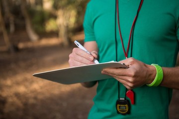 Trainer holding notepad in his hands in the forest on a sunny