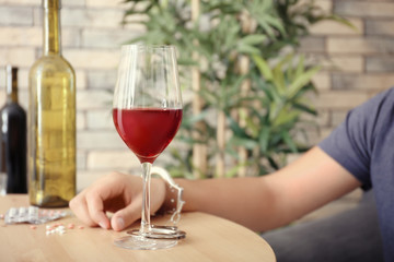 Man in handcuffs sitting at table with glass of wine. Alcohol dependence concept