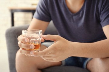 Man with glass of whiskey indoors. Alcohol dependence concept