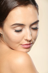 Obraz premium Beautiful young woman with eyelash extensions on color background