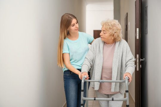 Young woman and her elderly grandmother with walking frame in corridor