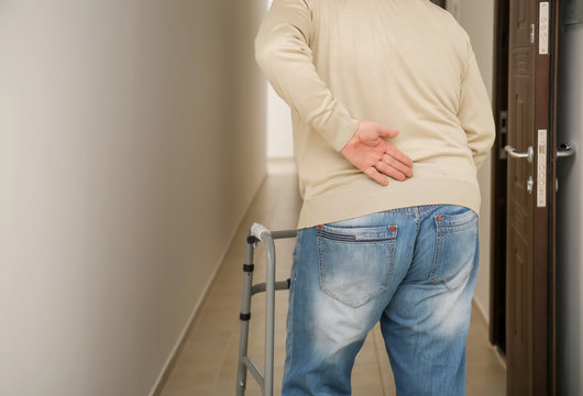 Elderly man with walking frame in corridor