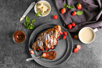 Delicious croissant with strawberries and chocolate syrup on plate