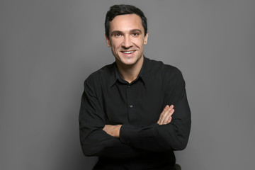 Attractive young man in black shirt on grey background