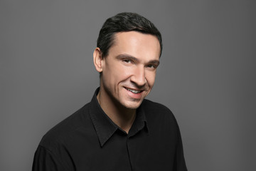 Attractive young man in black shirt on grey background