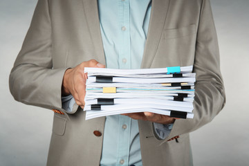 Man with stack of documents against light background