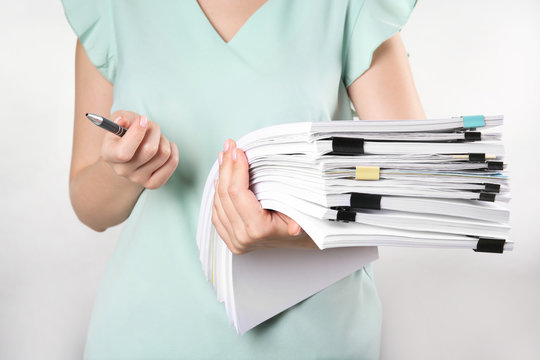 Woman with stack of documents against white background