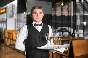 Waiter holding tray with glasses of champagne indoors