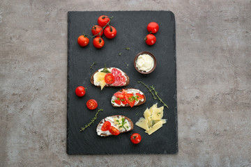 Slate plate with delicious bruschettas on grey background