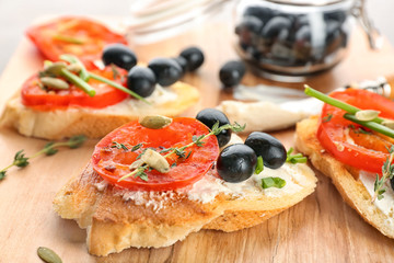 Tasty bruschetta with tomato and olives on wooden board, closeup