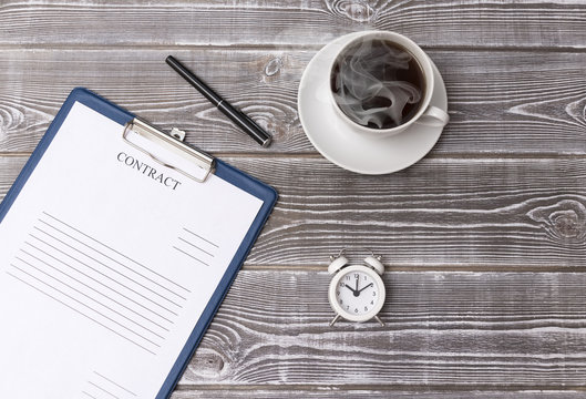 contract, cup of coffee, alarm clock on a wooden background