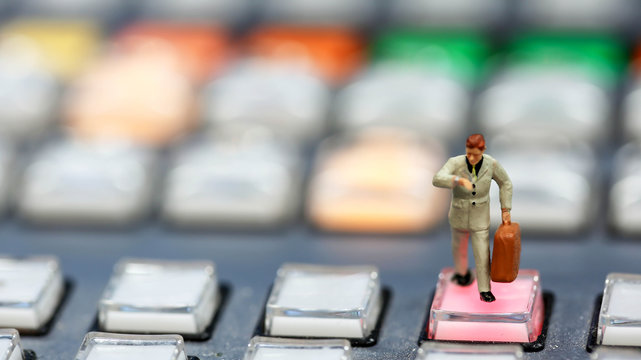 Miniature people : business man looking at watch and walk on the switcher control of Television Broadcast,color buttons