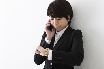 時計を見ながら電話するビジネスウーマン