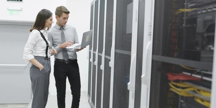 Team of people working in a data centre with rows of server racks and super computers. Shot on RED Helium 8K