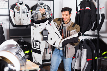 Male customer is choosing modern trousers in the sport store.