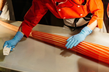Candy maker rolling handmade orange and white stripe candy by hands with gloves in Shiroi Koibito Park at Sapporo in Hokkaido, Japan.