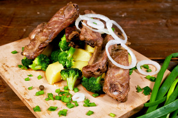 fried pork ribs with vegetables on a wooden table . Men's dinner