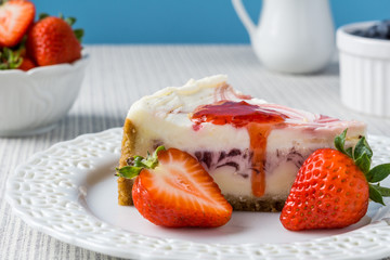 Delicious cheesecake with strawberry on a table against blue wall.