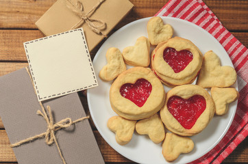 Homemade cookies in heart-shaped gifts and red paper hearts, greetings on Valentine's day, top view