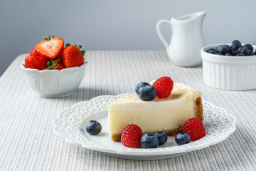 Delicious cheesecake with strawberry on a table against white wall.