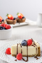 Delicious cheesecake with strawberry on a table against white wall.