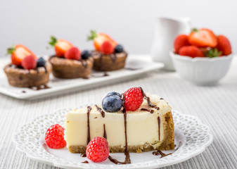 Delicious cheesecake with strawberry on a table against white wall.