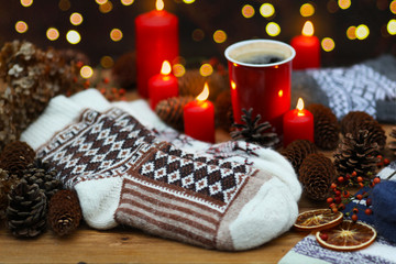 A festive winter composition with woolen socks, candles, cones and a garland.