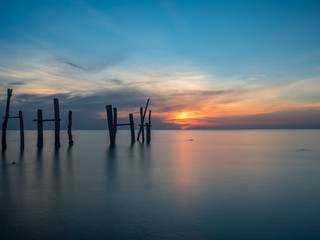 first light at the beach with broken wood bridge