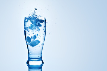 The ice cubes lapping in water glass. Water splashes, Background with copy space.